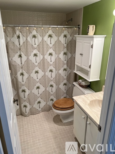 A bathroom with a green wall and a shower curtain with palm trees on it.