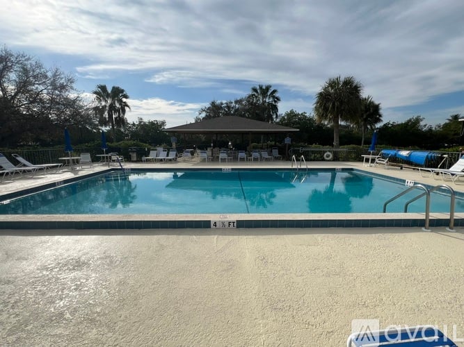 A large outdoor swimming pool with a sun lounger and a gazebo in the background.