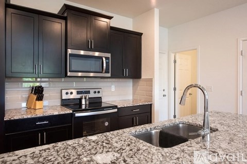 A kitchen with black cabinets and a granite countertop.