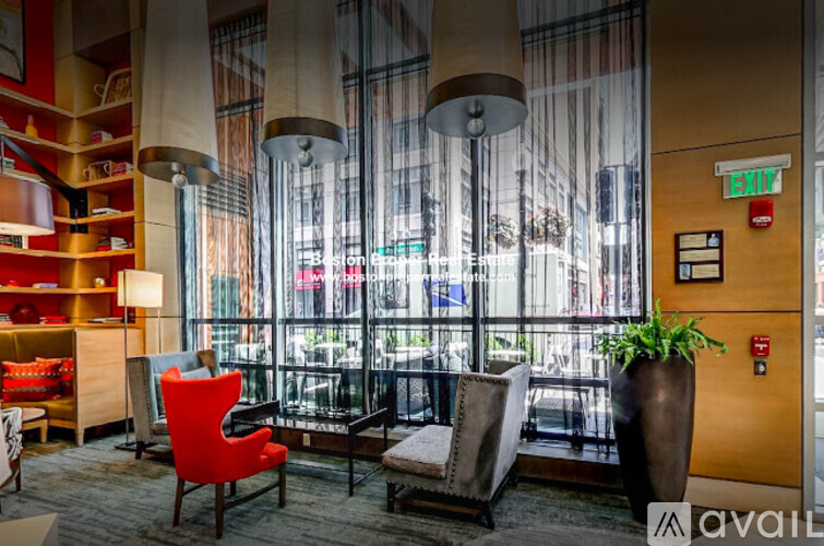 A living room with a red chair and a large window.