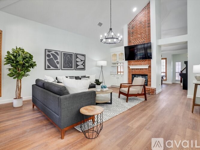 A living room with a grey couch, a wooden coffee table, and a TV mounted on the wall.