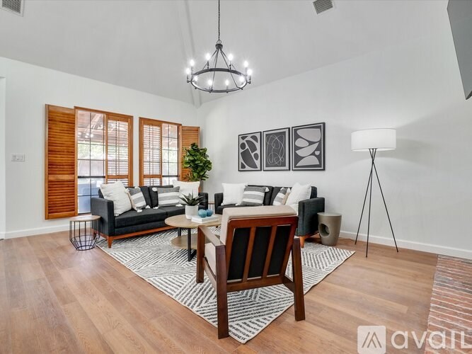 A living room with a black sofa, a wooden coffee table, and a rug with a black and white pattern.