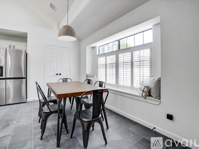 A modern dining room with a wooden table and black chairs.