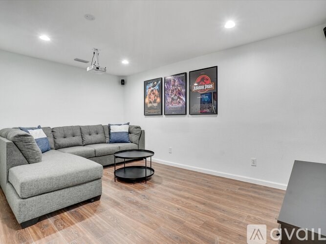 A living room with a grey sofa, a black coffee table, and two framed pictures on the wall.