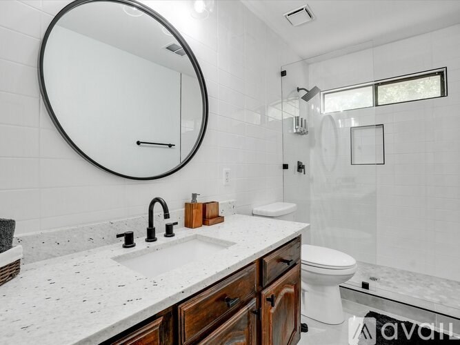 A bathroom with a white countertop and a round mirror.