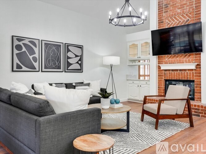 A living room with a grey couch, a wooden chair, a coffee table, and a fireplace.