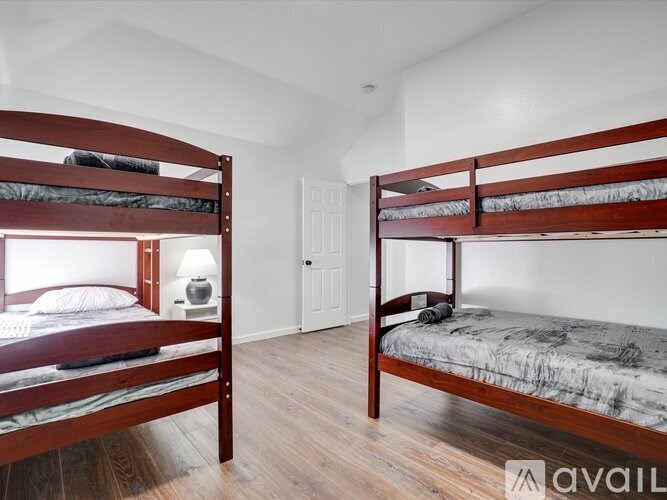 Two bunk beds in a room with wooden floors and white walls.