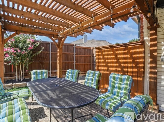 A patio with a table and chairs under a wooden pergola.