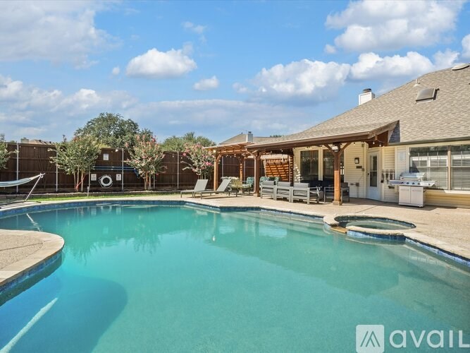 A large swimming pool in front of a house with a patio area.