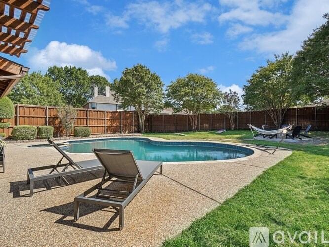 A pool with a chair and a table is surrounded by a fence.