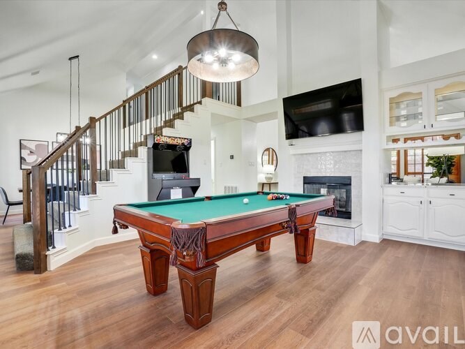 A pool table in a room with a staircase and a television.