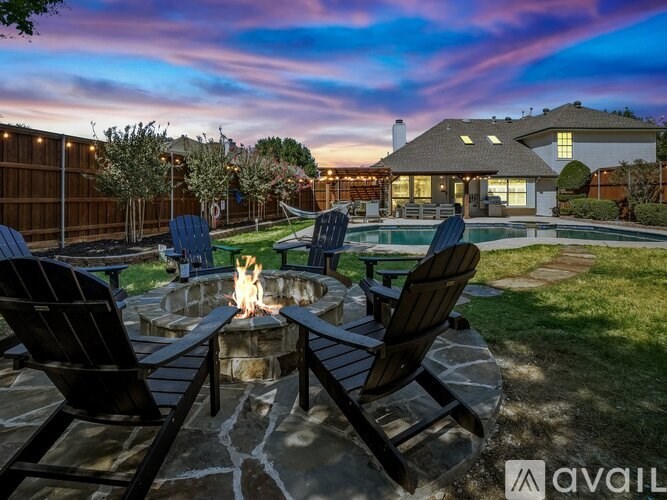 A backyard with a fire pit and chairs.