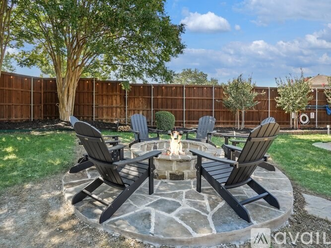 A dog sits on a fire pit in a backyard with chairs around it.