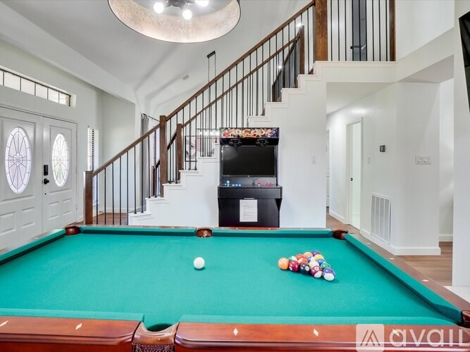 A pool table with a television in the background.
