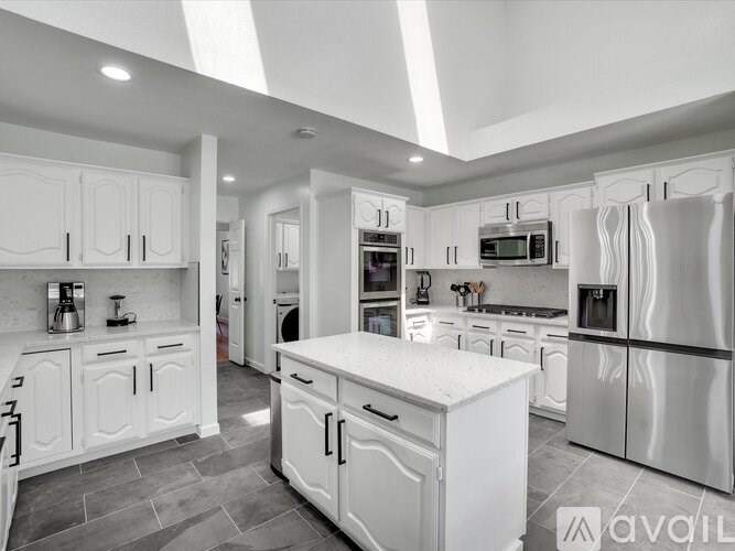 A modern kitchen with white cabinets and appliances.
