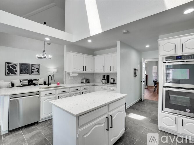 A modern kitchen with white cabinets and stainless steel appliances.