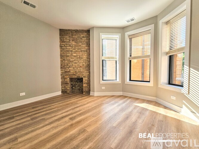 A room with a brick fireplace and wooden flooring.