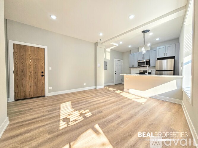 A spacious kitchen and living room with wooden flooring and modern appliances.