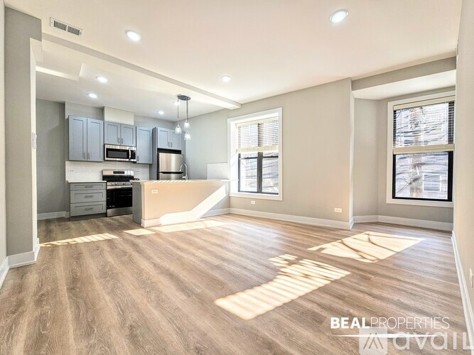 A spacious kitchen and living room with wood flooring and a large window.