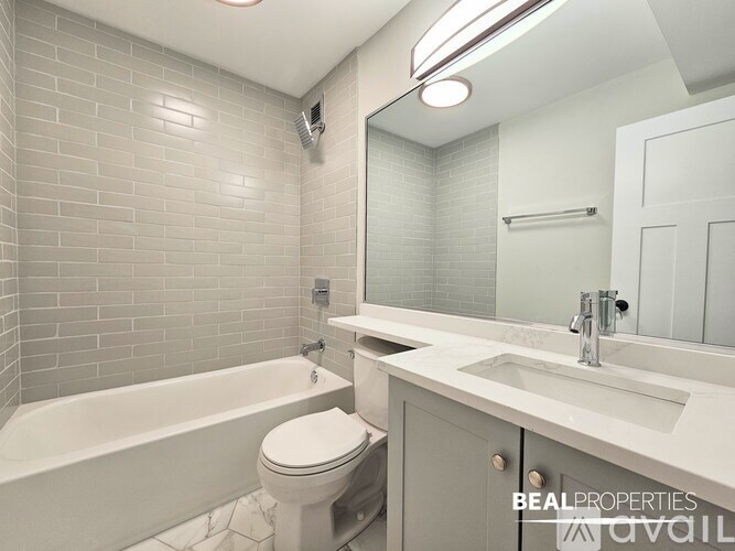 A well-lit kitchen with wooden flooring and a large island in the middle.