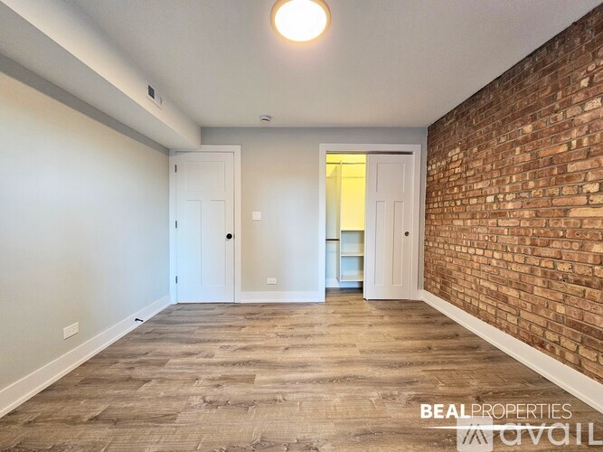 A spacious room with wooden flooring and a large window.