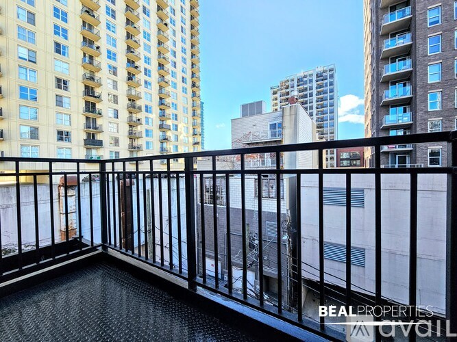 A balcony with a black railing and a view of other buildings.