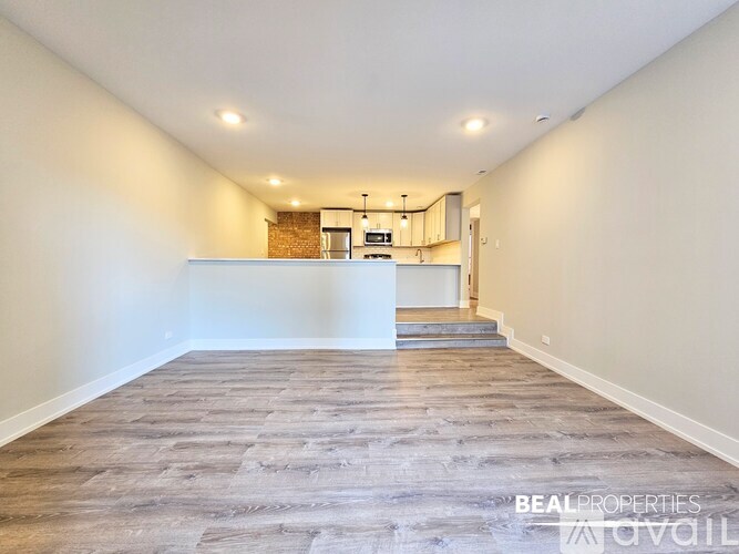 A modern kitchen with a stainless steel refrigerator and a wooden floor.