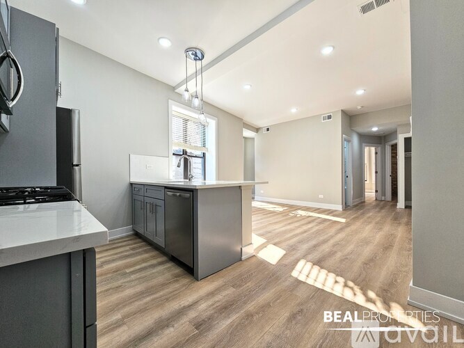 A modern kitchen with a stainless steel refrigerator and a wooden floor.