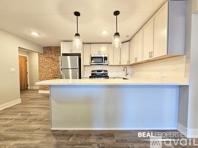A spacious room with wooden flooring and white walls, with a logo for BEAL PROPERTIES in the corner.