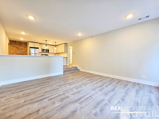 A spacious kitchen with wooden flooring and modern appliances.