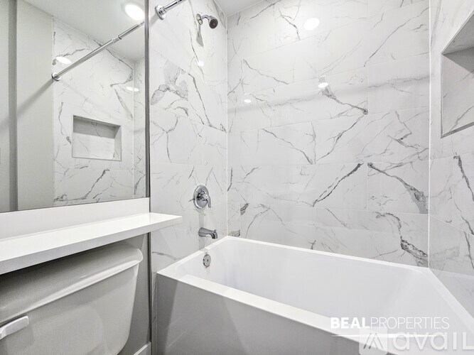 A white bathroom with a marble wall and a white bathtub.