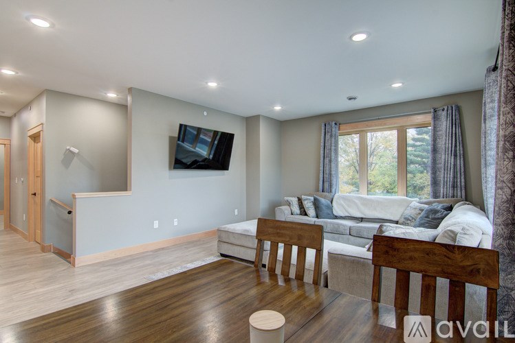 A living room with a couch, a television, and a window with curtains.