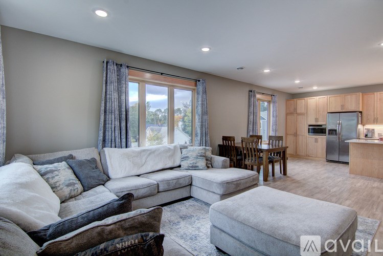 A spacious living room with a large couch and a kitchen area in the background.