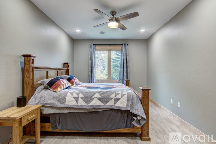 A bedroom with a bed, a ceiling fan, and a window with curtains.