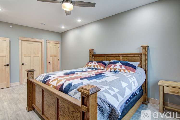 A bedroom with a bed, a ceiling fan, and a small table.