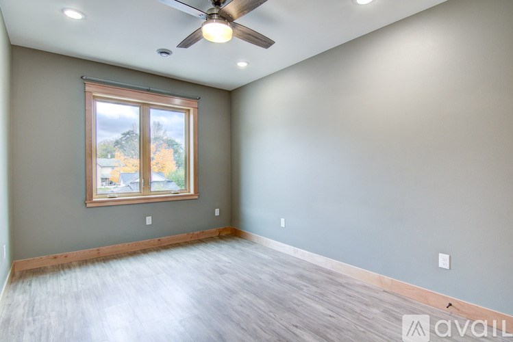 A room with a ceiling fan and a window showing trees outside.