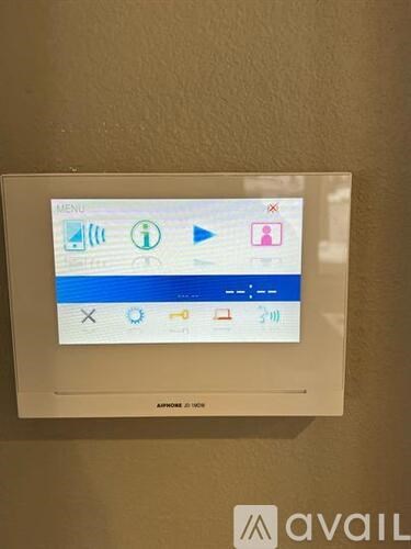 A wall-mounted touchscreen display with a menu button at the top.
