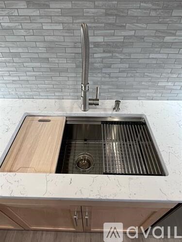 A kitchen sink with a wooden cabinet and a chrome faucet.