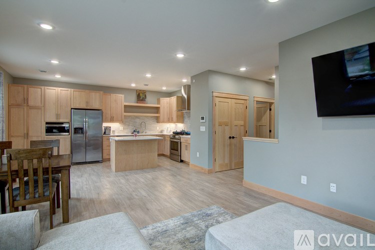 A modern kitchen with wooden cabinets and a television mounted on the wall.