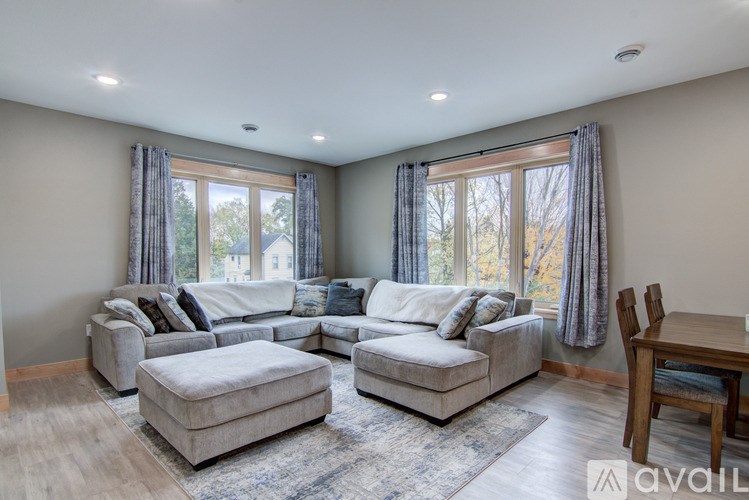 A spacious living room with a large sectional sofa, ottoman, and a dining table.