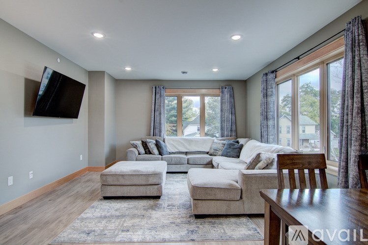 A living room with a white couch and a flat screen TV mounted on the wall.