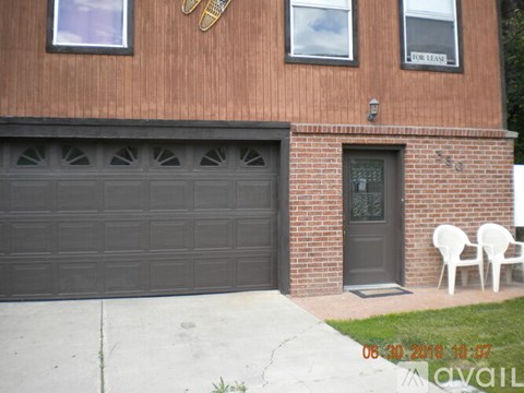A brown building with a black garage door and a sign that says "FOR LEASE".
