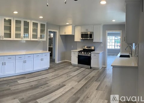 A kitchen with white cabinets and a wooden floor.