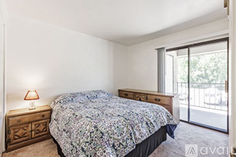 A bedroom with a patterned bedspread and a wooden bedside table with a lamp.