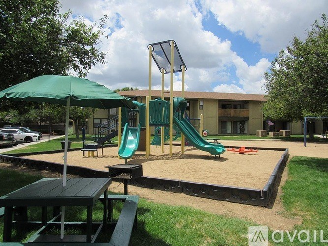 A playground with a green slide and a green umbrella.