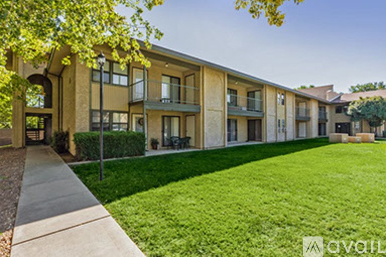 A row of apartment buildings with green lawns in front.