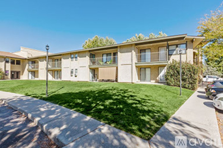 Apartment complex with green grass and trees in front.