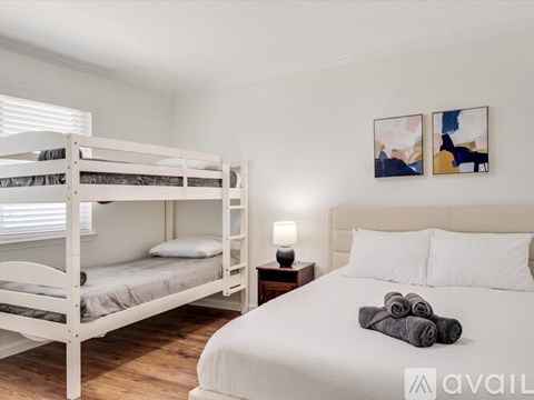 A bedroom with a white bed and a bunk bed with a white mattress.