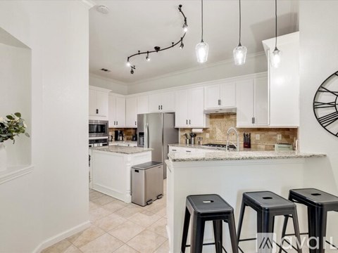 A kitchen with white cabinets and a marble countertop.