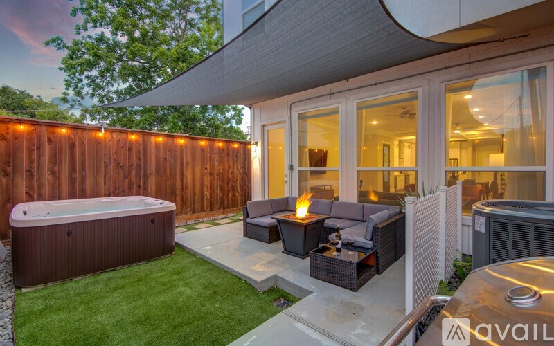 A backyard with a hot tub, patio furniture, and a wooden fence.